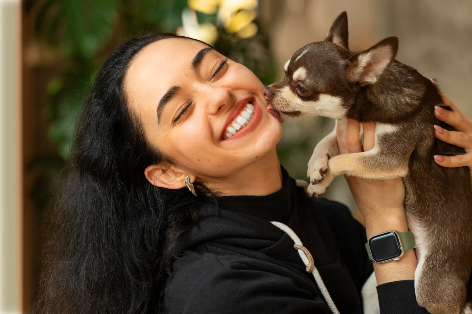A woman holding a small dog up to her face.